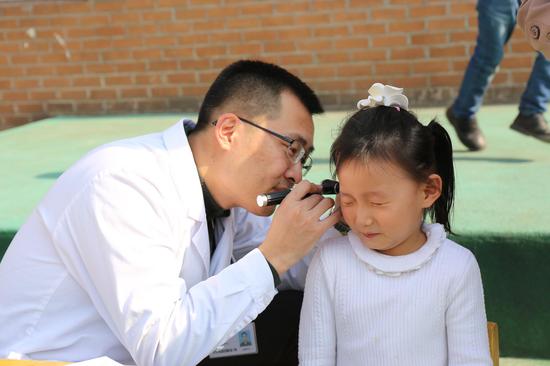图为北京清华长庚医院耳鼻咽喉头颈外科主治医师尹国平为孩子做电耳镜检查