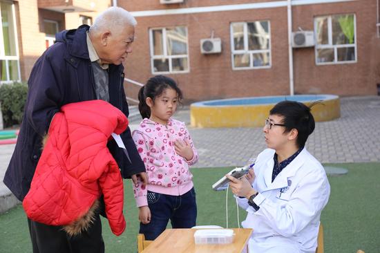 图为北京清华长庚医院耳鼻咽喉头颈外科听力技师梁思超为孩子进行听力筛查