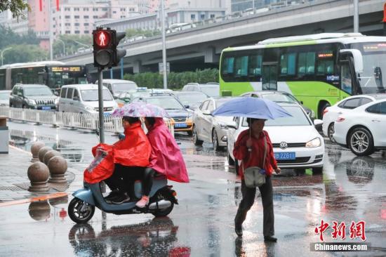  资料图：市民冒雨出行。中新社记者 贾天勇 摄