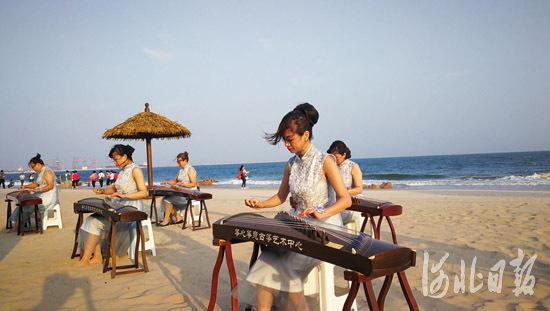 在海边沙滩上,有艺人奏响动听的音乐,欢迎观摩团一行。