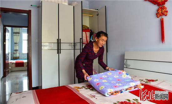 搬入康保县易地扶贫搬迁集中安置小区——怡安小区后,建档立卡贫困户金粉兰家装扮得温馨浪漫。这是8月28日金粉兰在家中整理房屋。河北日报记者耿辉摄