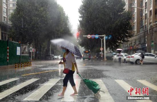 资料图：市民在雨中出行。中新社记者 张畅 摄