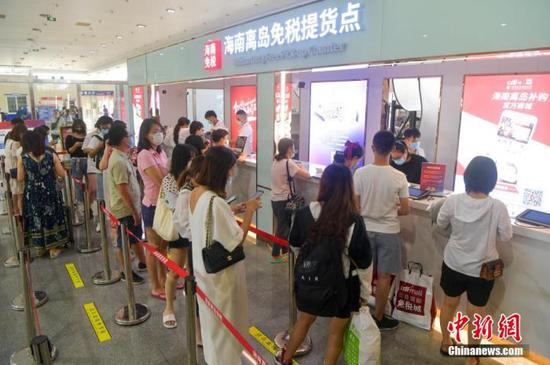 资料图:在海口新海港码头的海南离岛免税提货点,游客排队提货。 骆云飞 摄