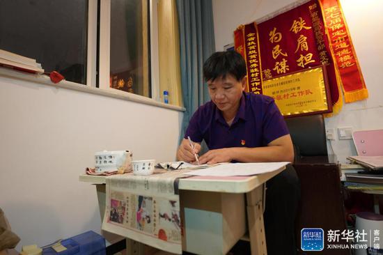 ↑黄文忠在记录扶贫日记(7月31日摄)。新华社记者 范世辉 摄