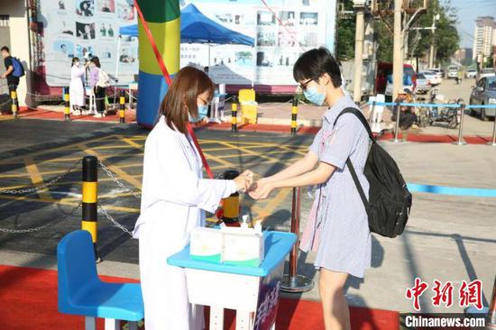 图为河北衡水中学开学第一天,工作人员为高一新生手部消毒。河北衡水中学供图