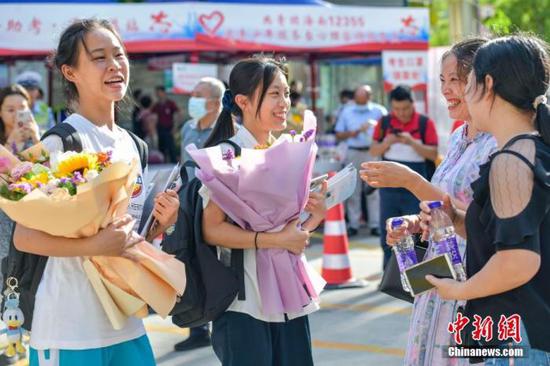 资料图:6月10日,海南省海口市海南中学考点外,家长为刚刚走出考场的考生送上鲜花。当日,海南省2021年高考结束 。 中新社记者 骆云飞 摄