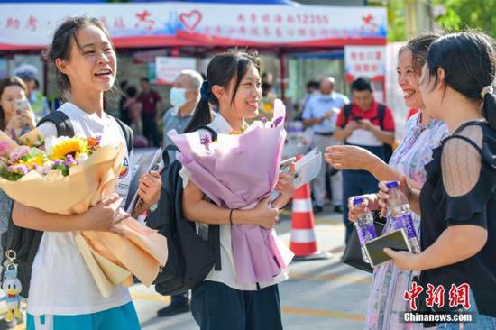 资料图：6月10日，海南省海口市海南中学考点外，家长为刚刚走出考场的考生送上鲜花。当日，海南省2021年高考结束 。 中新社记者 骆云飞 摄