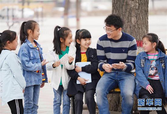 北京市海淀区中关村第三小学雄安校区派驻教师冯小宇同孩子们交流(2019年3月20日摄)。新华社发