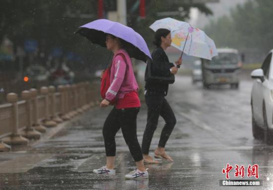 资料图:民众冒雨在北京街头出行。中新社记者 杨可佳 摄