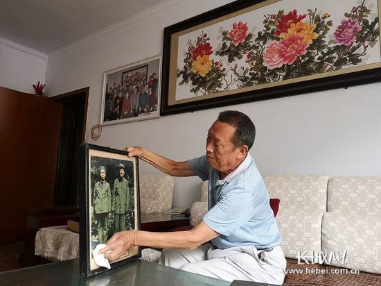 郭明祥老人擦拭着何长工和尹清平的相片。长城网记者 闫思宇 摄