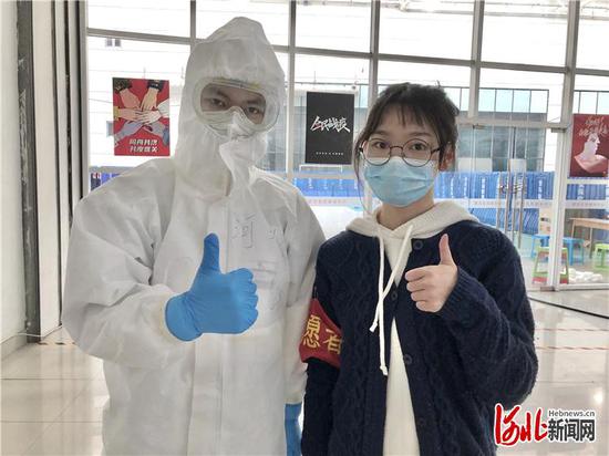 李玉海（左）和武汉江岸方舱医院志愿者摆出“胜利”手势，表达战胜疫情的决心。