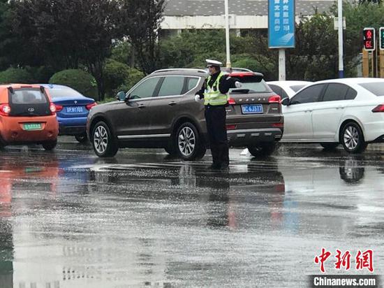 图为秦皇岛交警在雨中指挥交通。河北省交管局供图