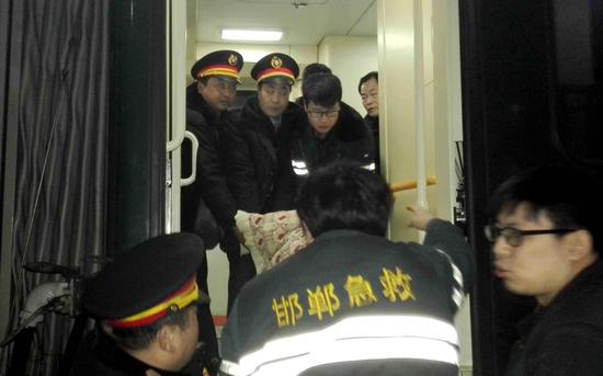 列车工作人员与急救中心医护人员一起抬旅客下车。