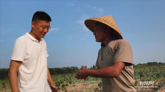 村民李国信向孟洋比划着梨的个头。长城网记者 冯硕 摄