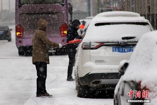 图为郑州市民清理车上积雪。中新社记者 王中举 摄