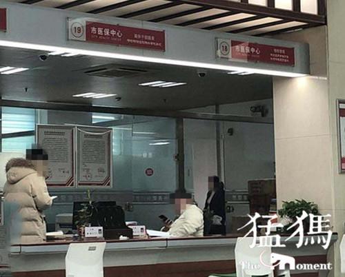 （信陽市行政審批中心醫保服務18、19號窗口，兩名工作人員玩手機）