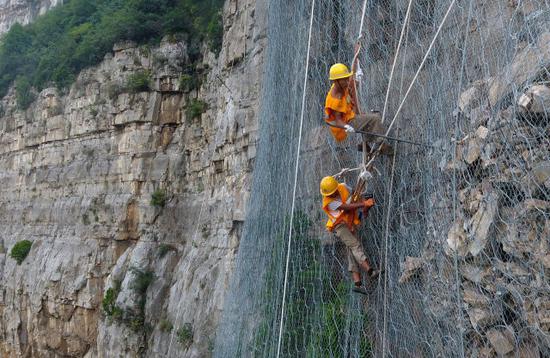 8月9日，抢险人员在侯月铁路柏枝隧道上方悬崖进行碎石作业（无人机拍摄）。