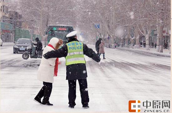 昨日一名交警雪中护送行人过路口 记者 张玉东 通讯员 邢红军 李霞 图