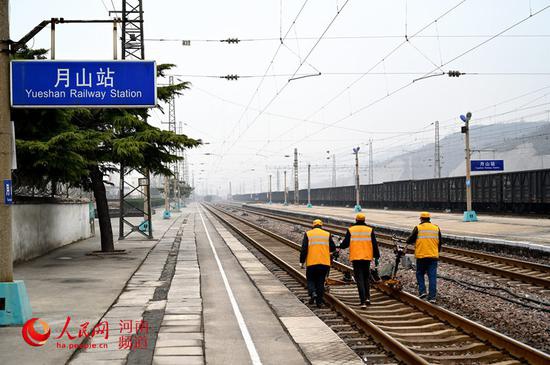 养路人推着作业机具走在铁路线上。  王占军摄