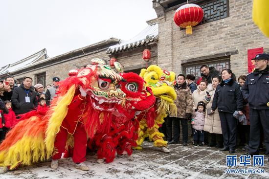 2019年2月10日，游客在河南安阳市文峰区仓巷街观看民间艺术舞狮表演。