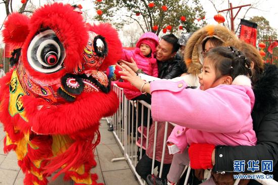 2月7日，河南许昌，人们在灞陵桥景区新春大庙会上观看舞狮表演。