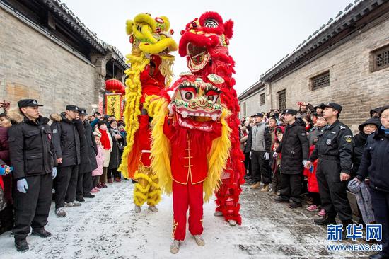 2019年2月10日,游客在河南安阳市文峰区仓巷街观看民间艺术舞狮表演。