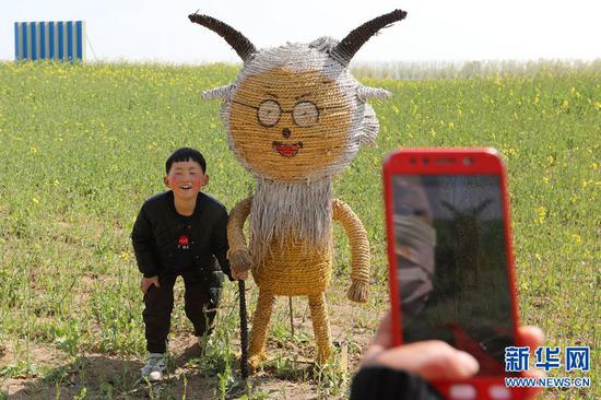 3月23日，河南封丘縣陳橋濕地公園，神態(tài)可掬的稻草人吸引了一位小朋友。