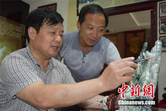 图为石佛寺镇玉雕匠人探讨玉雕设计 镇平县委宣传部供图