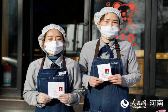 2月25日,河南省平顶山市宝丰县一家蛋糕店的员工展示工作证。何五昌 摄