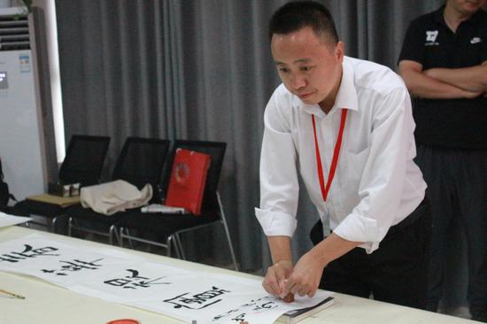 中国书法家协会会员、河南省文艺志愿者崔涛正在为作品盖章