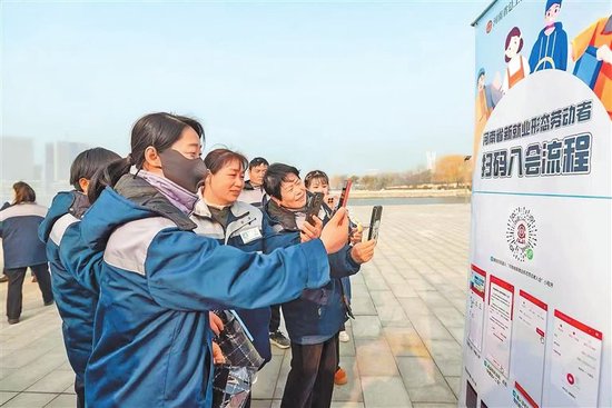 在“暖心冬日·工会在身边”冬季送温暖活动现场，新就业形态劳动者正在扫码入会。 王威 摄