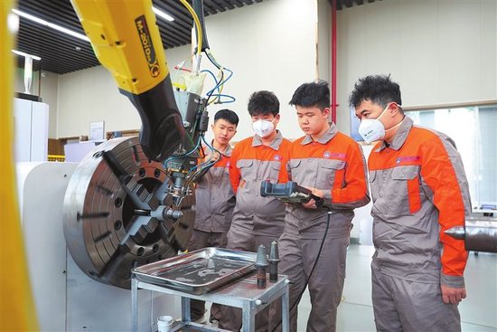 在学校的激光加工中心，李明珅（右二）操作激光熔覆设备进行截齿修复。 受访者供图