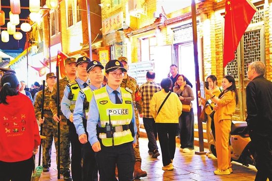 图①　10月1日，安阳仓巷街游人如织。安阳市公安局文峰分局东大街派出所组织民警联合义警队伍在古街巡逻，守护街区平安。 冯永华 摄