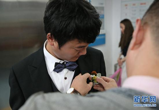 杨枫换上礼服,婚庆工作人员为他带上胸花。