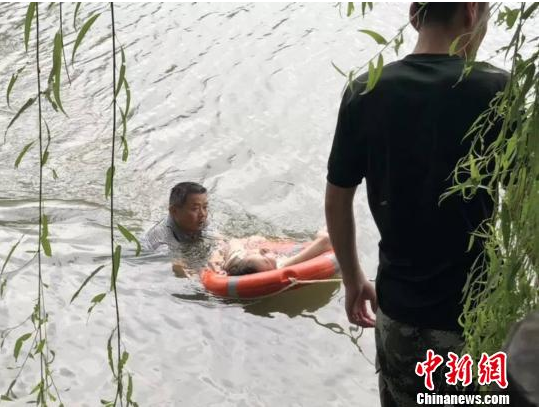 图为金诚老师正在河中救人。