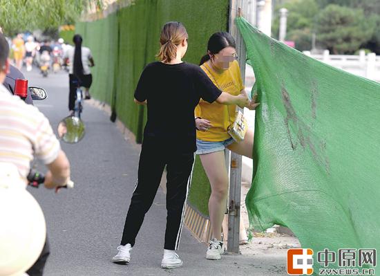 7月1日下午，花园路与东风渠交叉口，一女子从围挡缝隙穿过 郑报全媒体记者 周甬 图