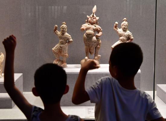 8月14日，在河南洛阳博物馆，两名小朋友在模仿彩绘天王俑的动作。