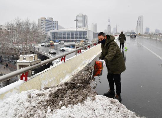 2月10日，郑州市政部门工作人员清理路面积雪。