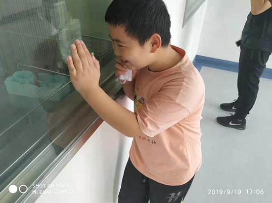  路子寬在醫院隔著玻璃笑著與父親聊天。受訪者供圖