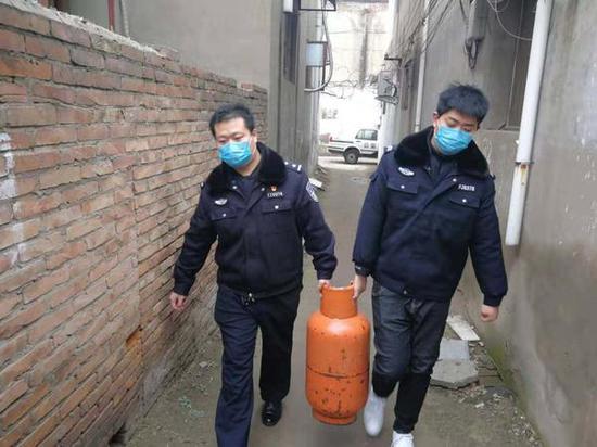陈龙(左)和同事给老人送煤气罐