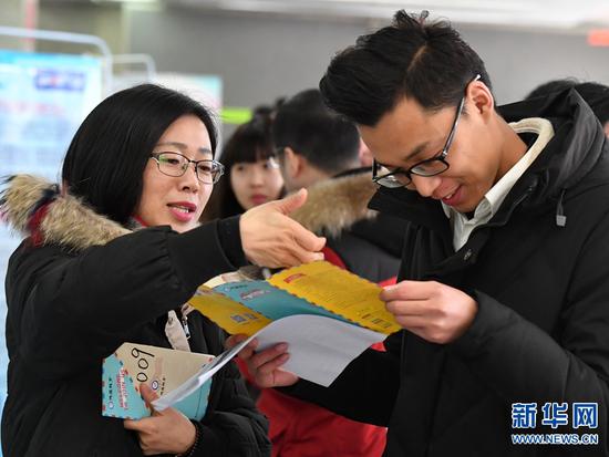 2月13日，在河南人才市场，用人单位代表（左）与求职者交流。