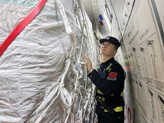 边检民警徐朝阳穿行在货物缝隙之间，仔细检查飞机每个角落。本报全媒体记者 赵同增 摄