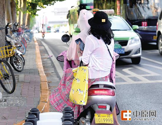 昨日下午，花园路东风路口，一辆电动车违章载人在快车道内逆向行驶 郑报全媒体记者 周甬 图