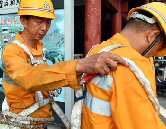 8月9日,抢险小组组长马建宏(左)为同事检查安全绳捆绑情况。