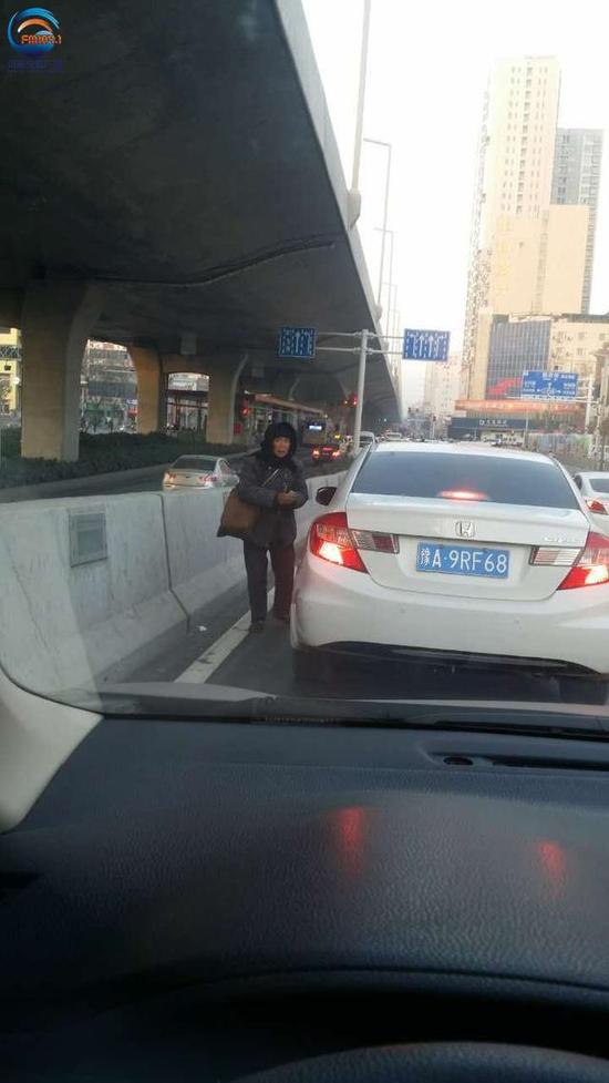 郑州多路口现乞讨者 拿鸡毛掸抹布扑车而来