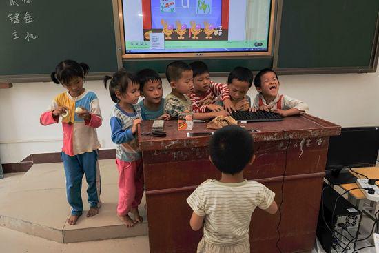 4月11日,大华寮村教学点,学生们围观上课用的电脑。这是该教学点第一次使用多媒体教学设备,也是大部分学生第一次见到电脑。