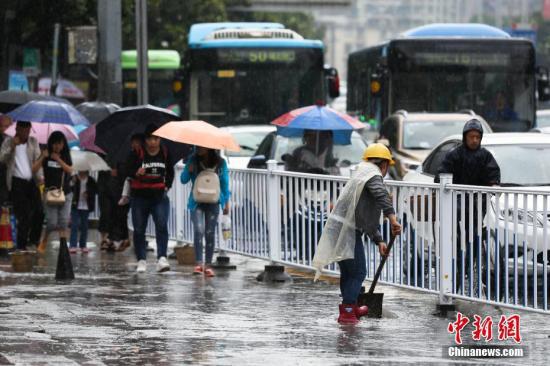 6月12日，貴陽持續降雨造成貴陽市多處路段嚴重積水，市民出行受阻。圖為貴陽市環衛工人清理路面積水。 黃芷昕 攝