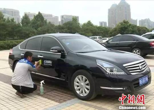 图为新乡市相关部门工作人员为公务用车张贴标识。新乡市政府新闻办供图