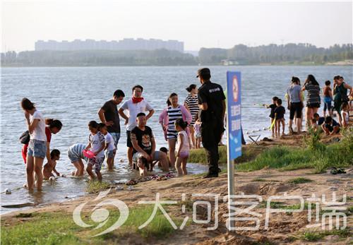 在龙湖码头旁很多市民带着孩子玩水,工作人员为了他们安全提醒他们上岸。