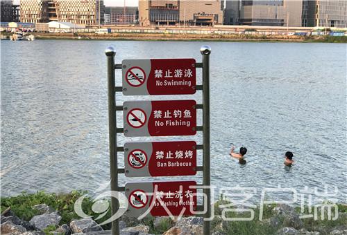 尽管岸边树立着醒目的警示牌,仍然有市民下水游泳。
